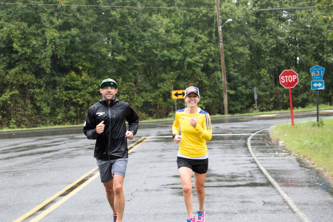 ​Jack Braconnier training with an athlete in poor weather with smiles on their faces.